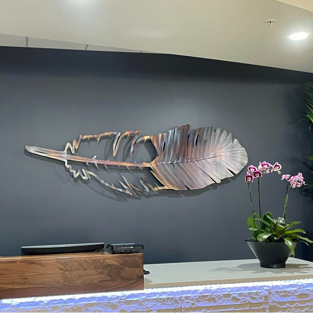Feather metal wall art displayed with flowers