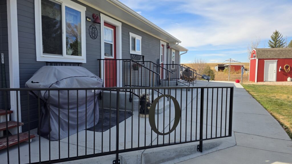 Black metal accessibility ramp railing outside a gray building